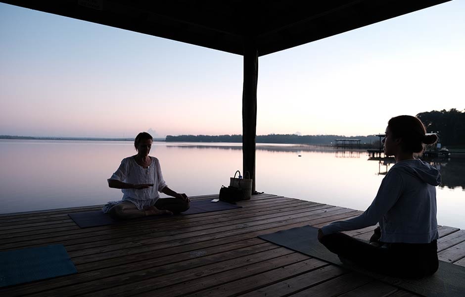 Morning meditation guidance at the pristine lake during a wellness retreat at the Amrit Yoga Institute