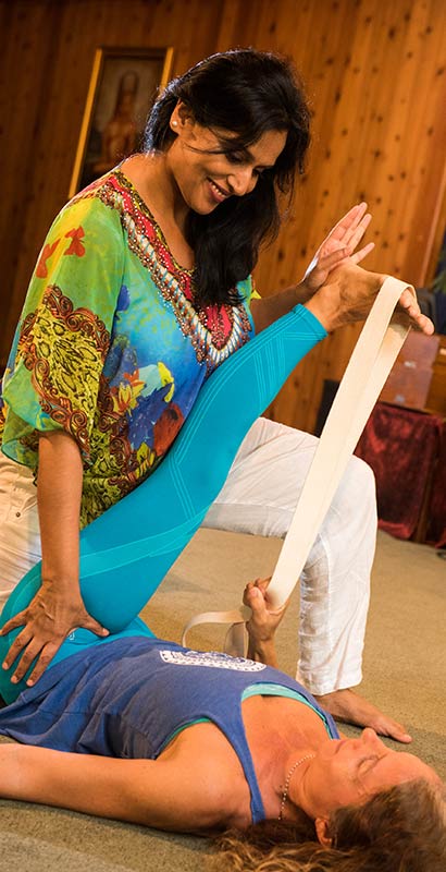 Kamini Desai demonstrating a yoga therapy stretch using straps to assist the client
