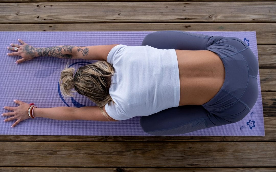 Top down view of woman in child's pose on a purple yoga mat