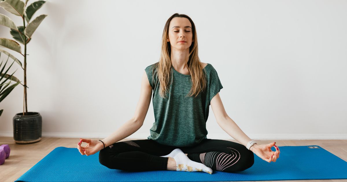 Woman meditating on a yoga mat to break the worst habit of living for what comes next.