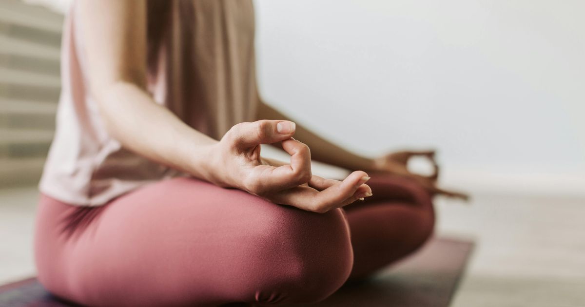 Person practising meditation in a seated yoga pose with hands in a mindful mudra