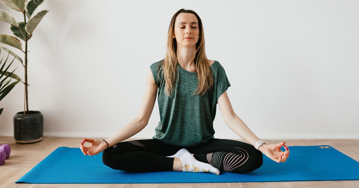 Woman meditating on a yoga mat while practicing yoga with mindful awareness